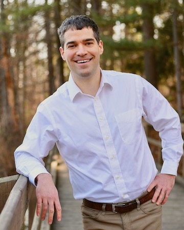 Dr. Nathan Lamkin smiling outdoors beside a wooden railing